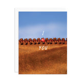 A greeting card featuring a close-up photograph of a chestnut horse's braided mane under a blue sky, with the words 'I' and 'YOU' and a red heart charm in the center. A white envelope is partially visible behind the card on a white background.