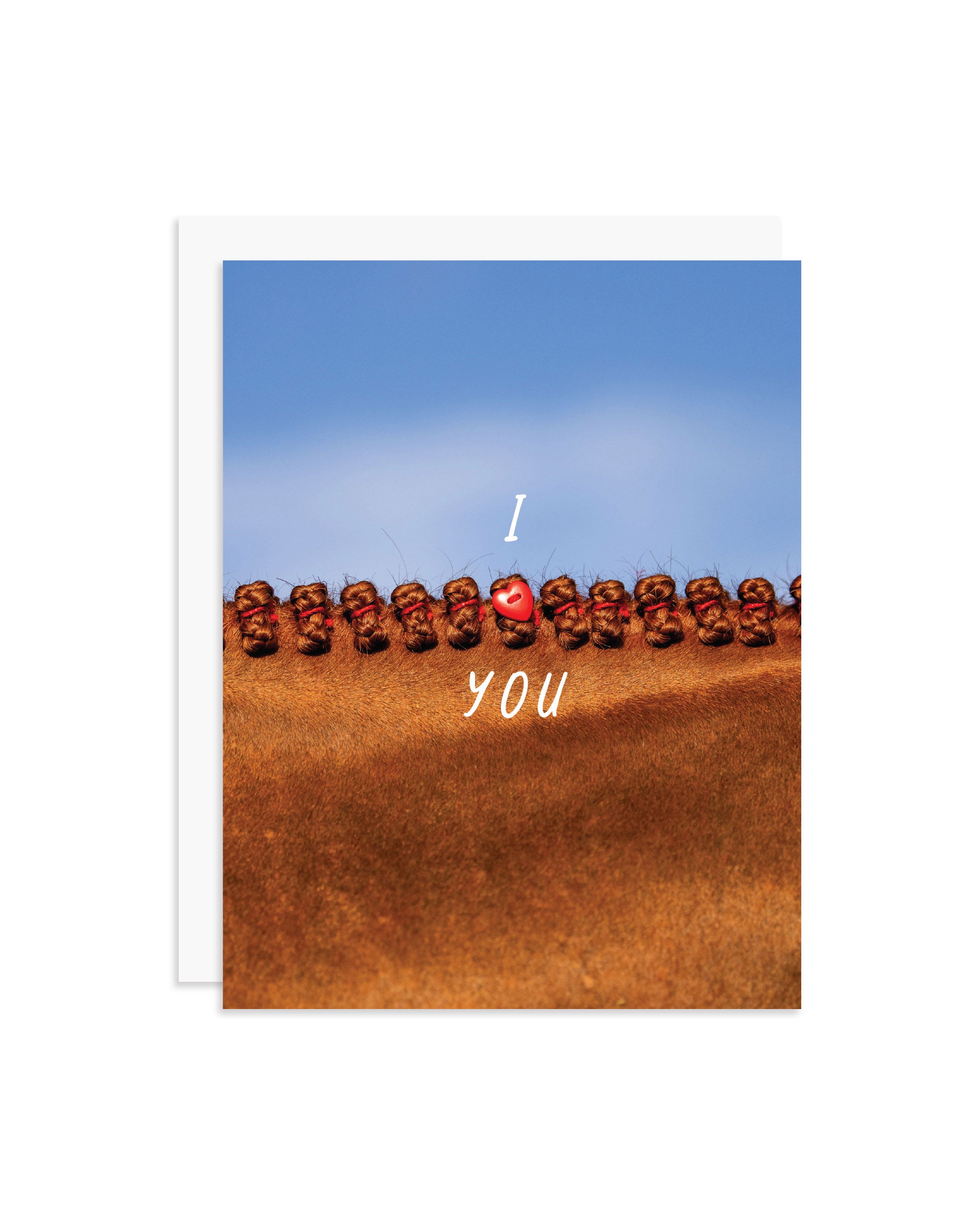A greeting card featuring a close-up photograph of a chestnut horse's braided mane under a blue sky, with the words 'I' and 'YOU' and a red heart charm in the center. A white envelope is partially visible behind the card on a white background.