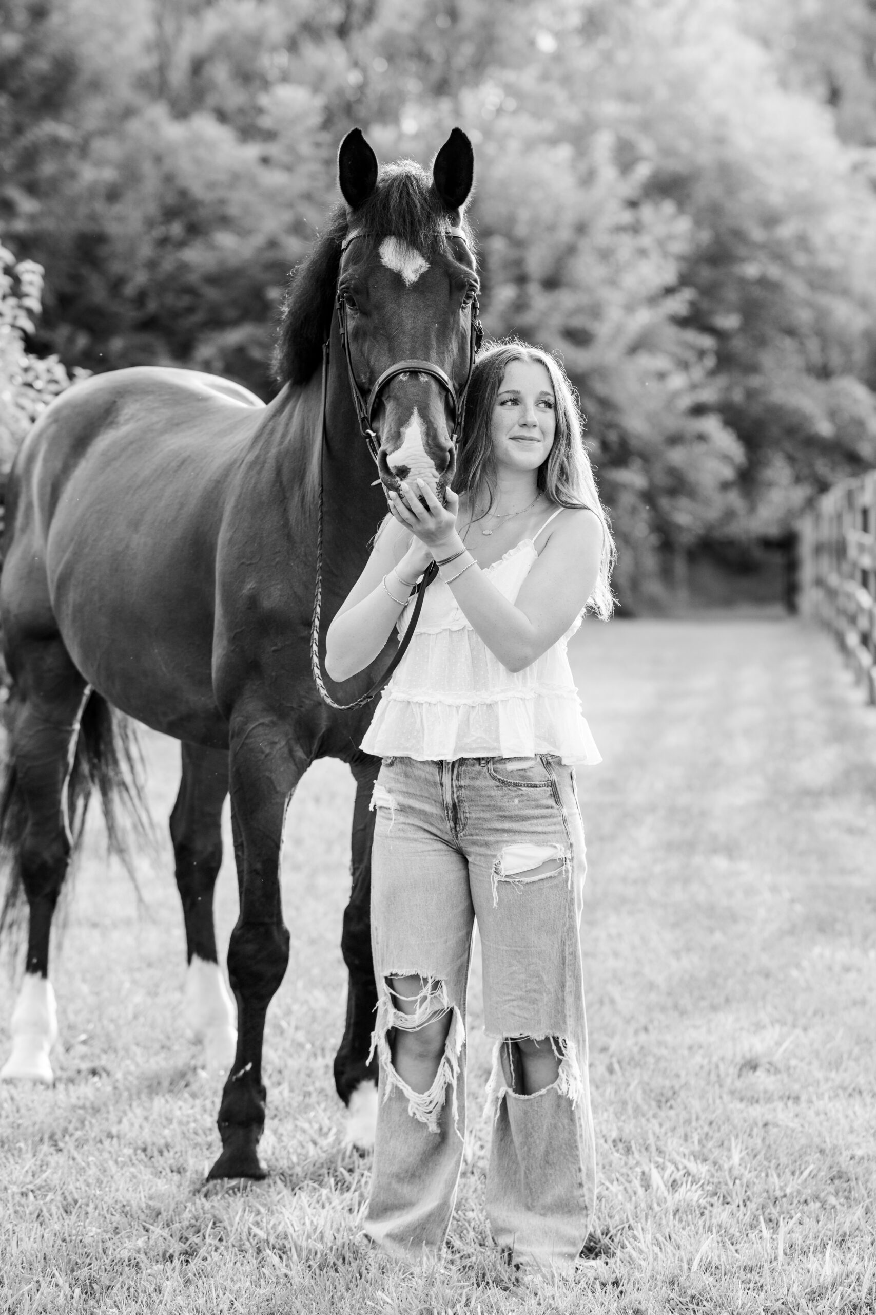 Equestrian senior girl stands beside her horse during warm golden hour light in Carmel, Indiana