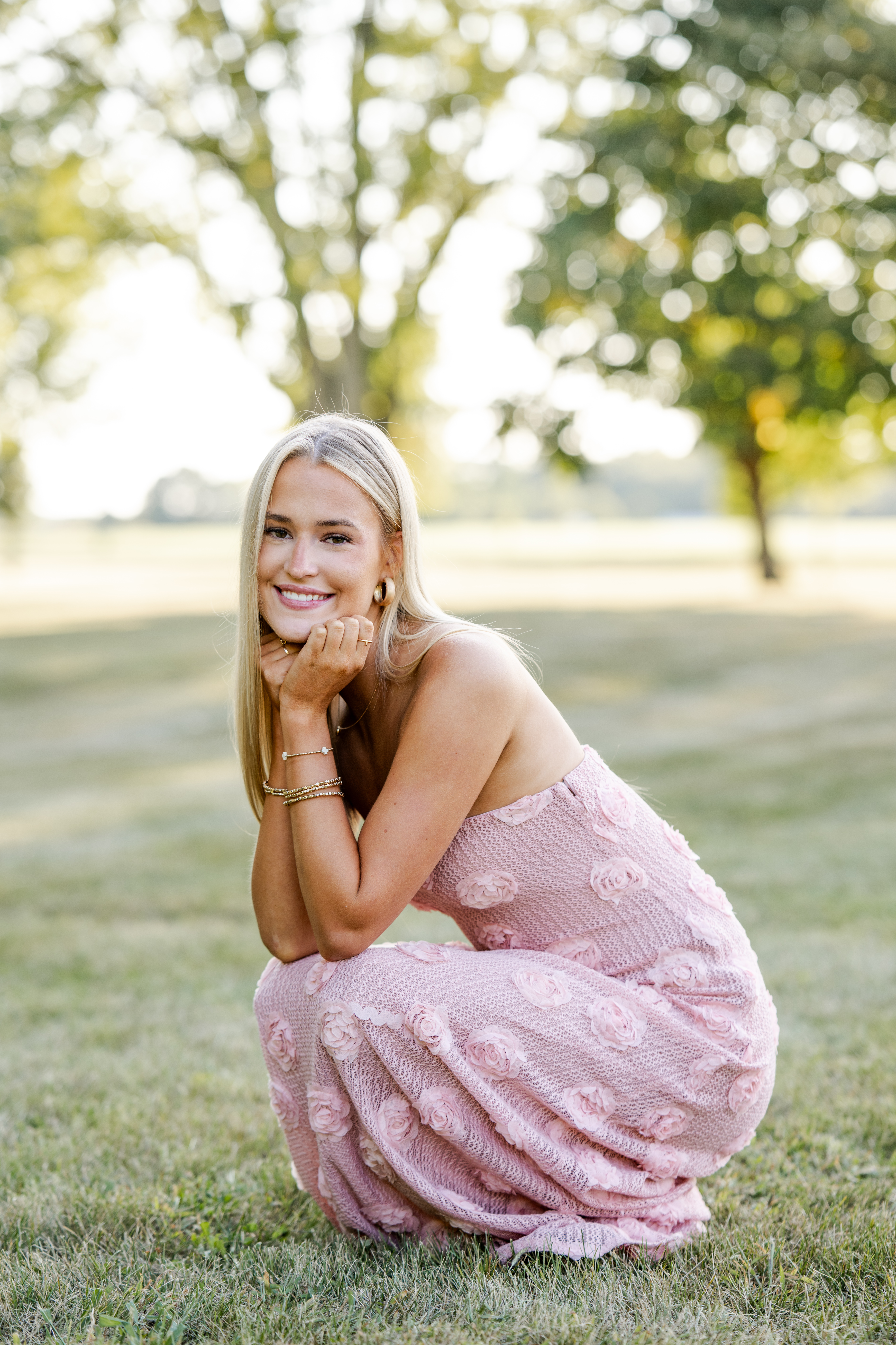 Westfield High School senior kneeling in the grass during golden hour photo session