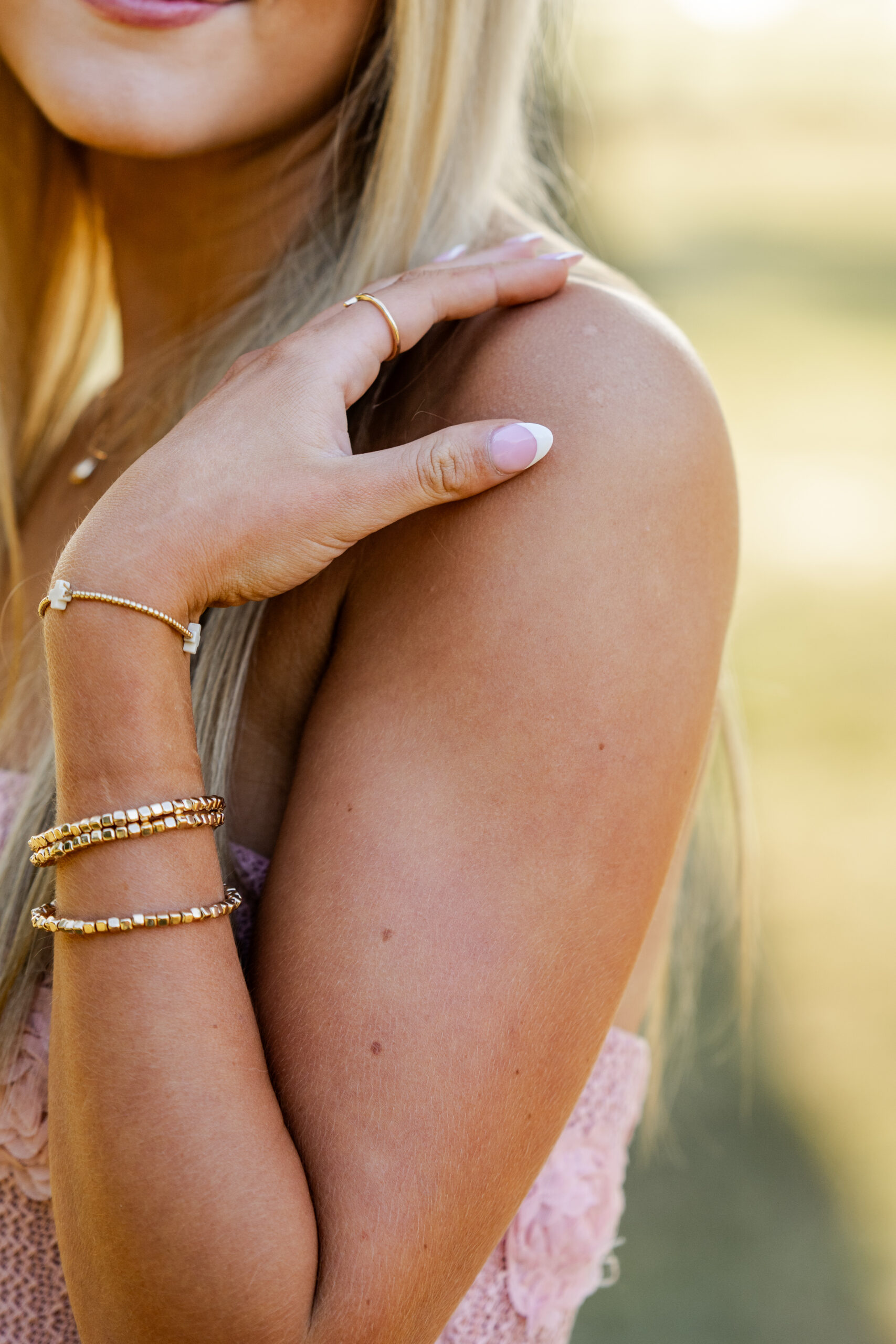 Close-up detail of senior’s bracelets and nails during golden hour photo session by Kate Kosnoff Creative