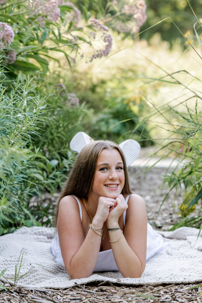 High school senior girl relaxes on a picnic blanket during golden hour portraits with Indianapolis photographer Kate Kosnoff