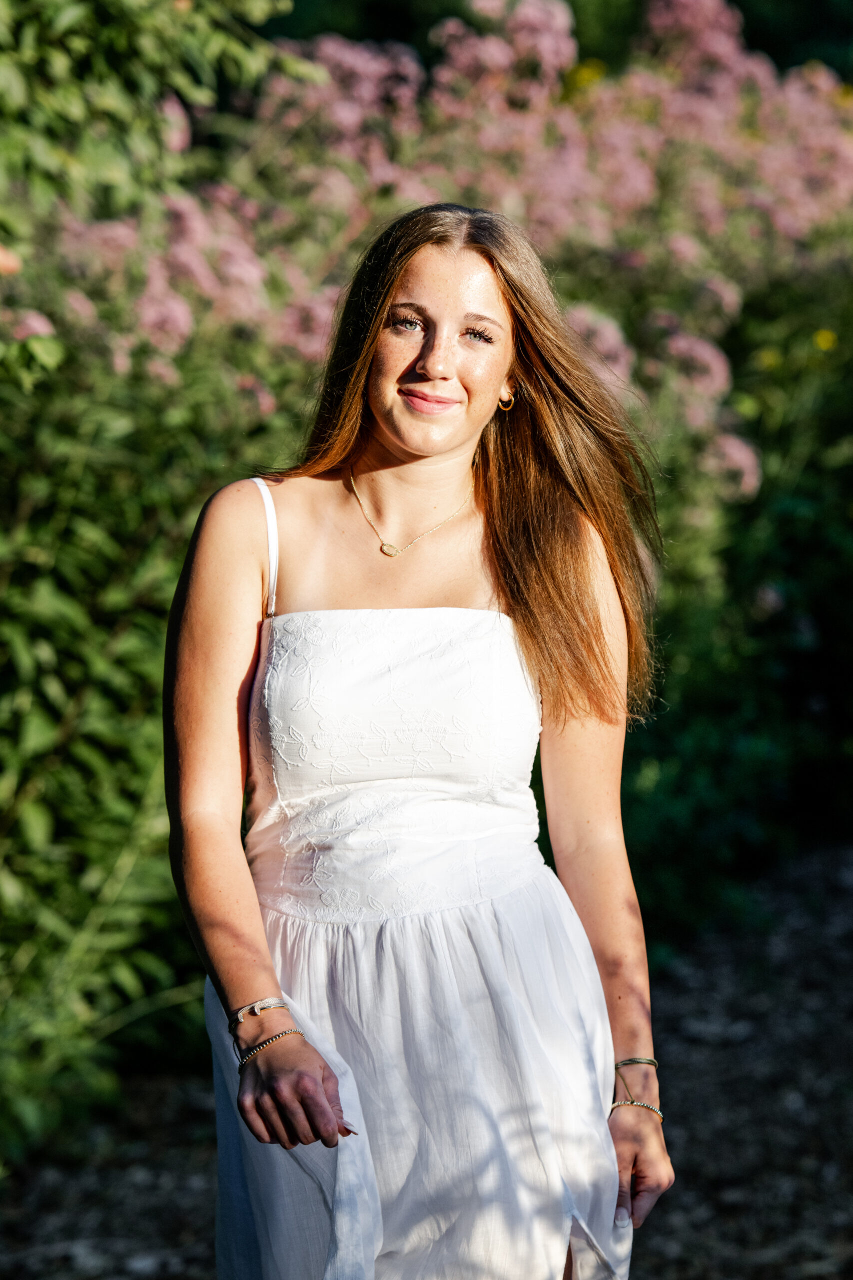 Brownsburg High School class of 2026 senior girl smiles beside purple flowers at Newfields in Indianapolis